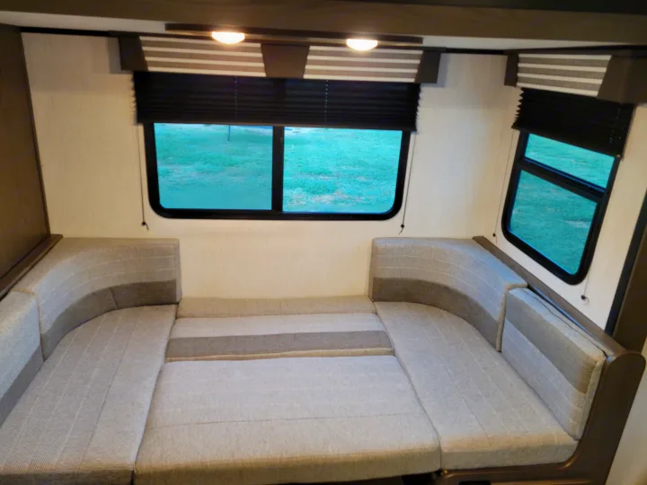 Inside a spacious RV rental: U-shaped dinette seating converts to a comfy bed, with windows & shades.. Cruiser RV MPG Ultra Lite 2022