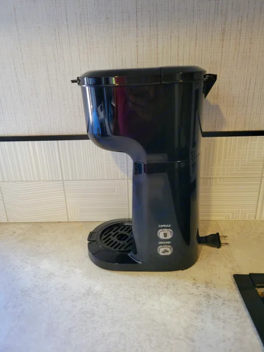 This black coffee maker, perfect for your rv rental kitchen, offers capsule and ground brewing options on a light-colored counter.. Cruiser RV MPG Ultra Lite 2022