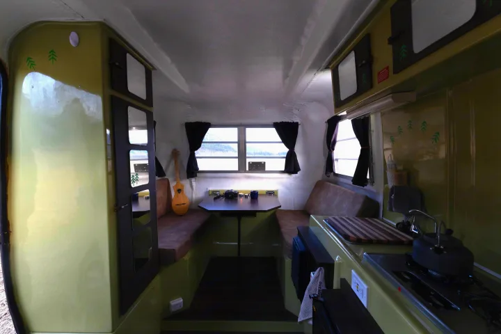 An RV rental's cozy interior, showcasing a small kitchen, dining space, and built-in seating for travel.. Trillium Rv 1300 1976