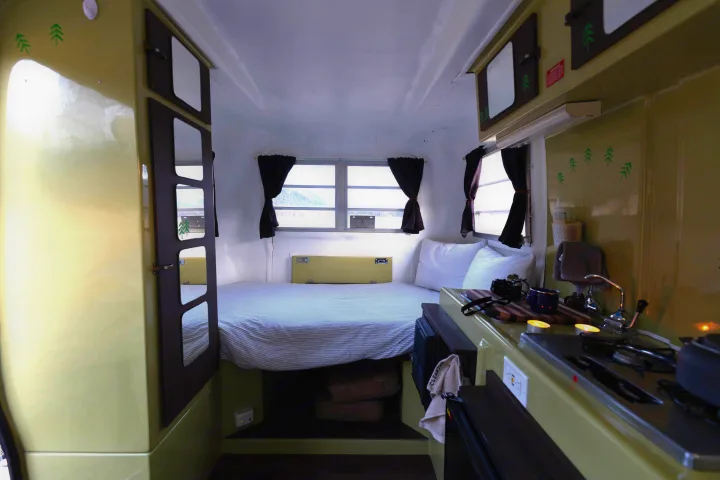 Cozy rv rental interior: A bed, bright windows, and a compact kitchenette with stove and sink.. Trillium Rv 1300 1976