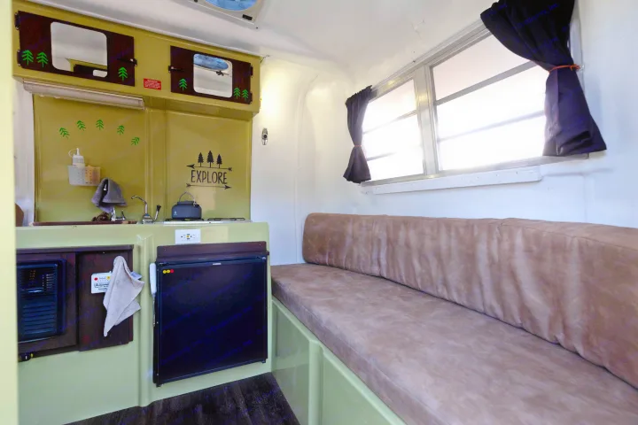 Cozy RV rental interior with kitchenette, "EXPLORE" decor, and comfortable bench seating, perfect for travel.. Trillium Rv 1300 1976