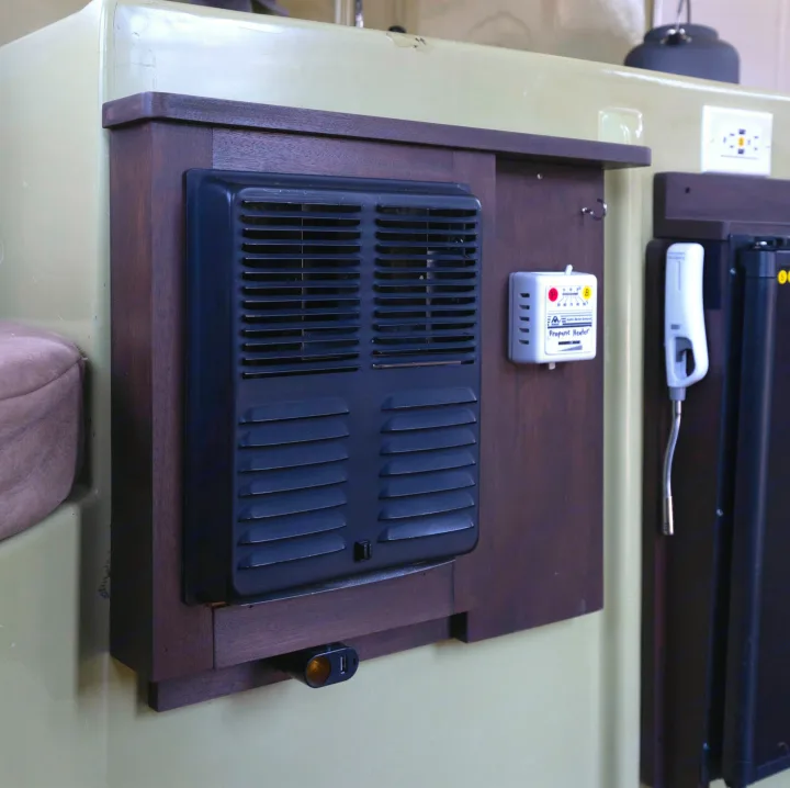 Essential RV rental amenities: wall-mounted propane heater with controls, 12V/USB outlet, and general power outlet.. Trillium Rv 1300 1976