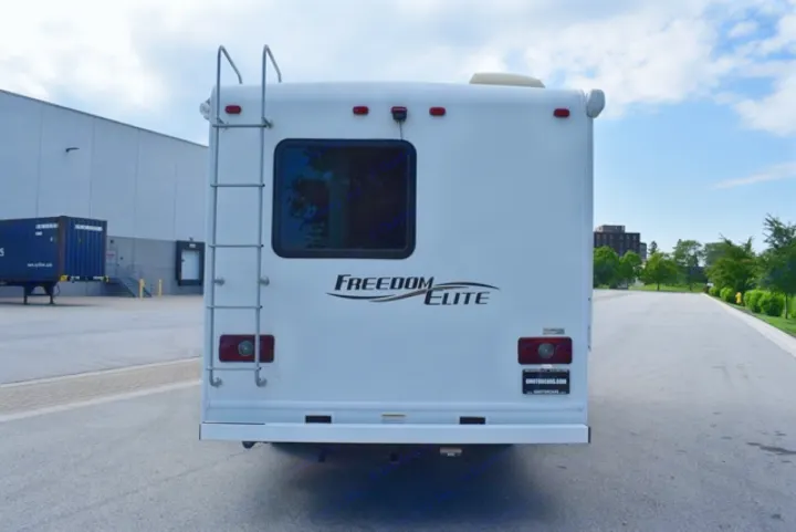 Rear view of a white Freedom Elite RV rental with ladder & window, parked on asphalt. Ideal motorhome for travel.. Thor Freedom Elite 2016