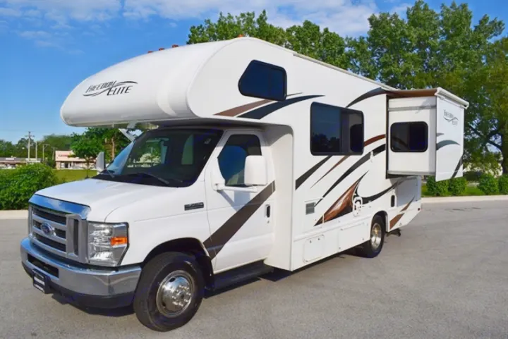 White Ford Class C RV rental with brown/black graphics & extended slide-out, parked on asphalt for your travels.. Thor Freedom Elite 2016