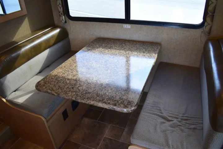 An inviting RV rental dinette area featuring a granite-patterned table and two cozy benches, with an "EXIT" sign visible.. Thor Freedom Elite 2016