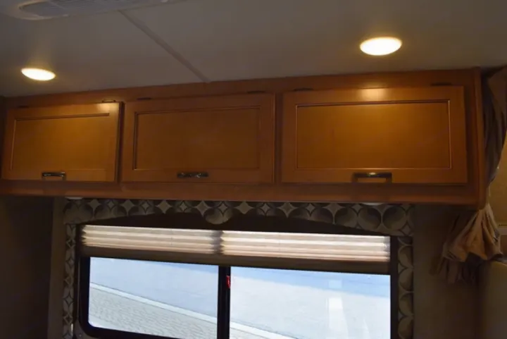 RV rental interior: Overhead wooden cabinets, a window with blinds, and ceiling lights provide comfort and storage.. Thor Freedom Elite 2016