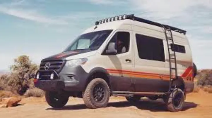 A rugged, lifted Mercedes Sprinter adventure van, ideal for RV rental, on a desert trail. Roof rack & ladder visible.. Storyteller Overland Beast Mode 2023