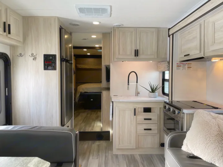 Spacious, modern RV rental interior featuring a full kitchen with light cabinets, refrigerator, and a visible bedroom.. Forest River Forester 3251DSF 2023