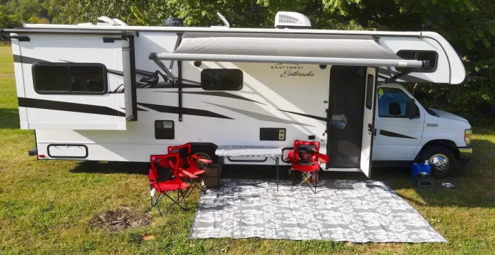 White East to West Entrada RV rental parked outdoors, ready for camping. Awning and slide-out extended with outdoor furniture.. East to West Entrada 2600DS 2022