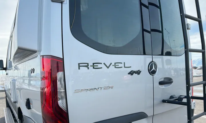 Rear view of a white Winnebago Revel 4x4 Mercedes Sprinter camper van, showing its badging and ladder. Perfect for rv rental adventures.. Winnebago Revel 2020