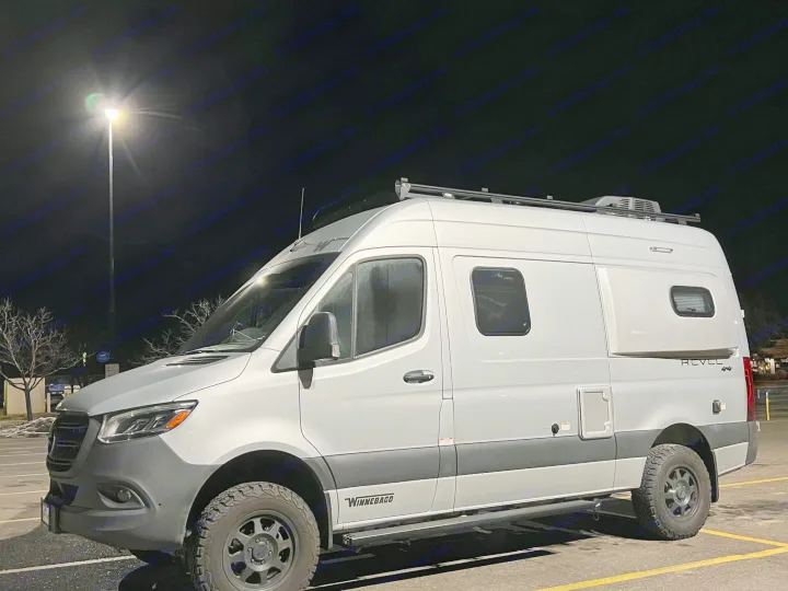 A sleek silver Winnebago Revel 4x4 camper van, often chosen for RV rental adventures, parked at night.. Winnebago Revel 2020