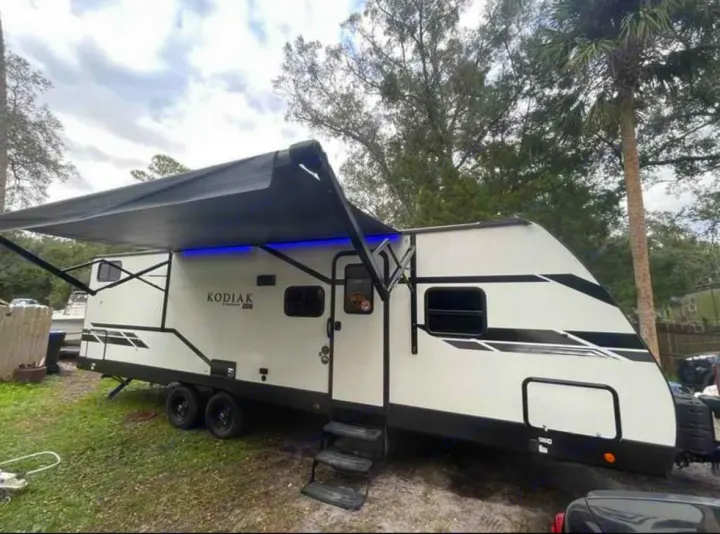 Ready for your RV rental adventure! This white Kodiak travel trailer features a deployed awning with blue LED lights.. Dutchmen Kodiak SE 2021