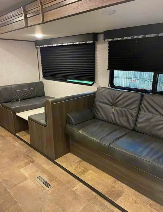 RV rental interior: booth dining area, sofa, and dark blinds. A compact, comfortable living space.. Dutchmen Kodiak SE 2021