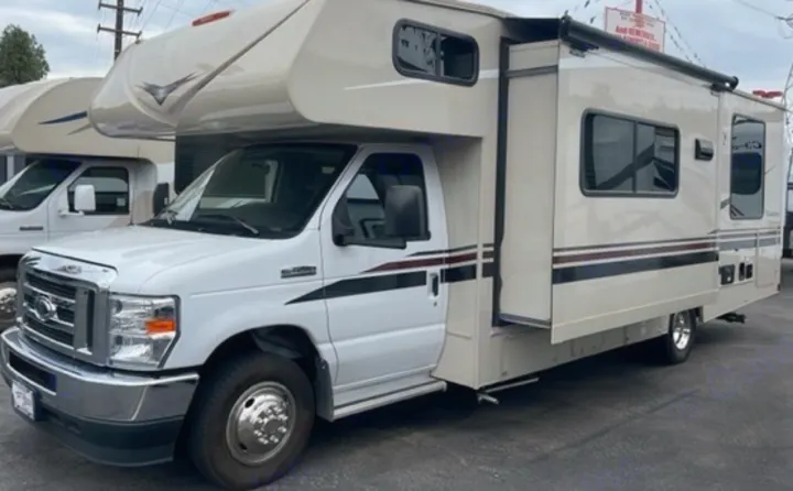 White RV rental parked outdoors, its side slide-out extended, ready for your next adventure.. Other Leprechaun 2022