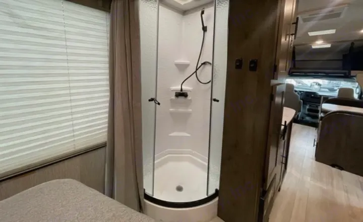 This RV rental offers a compact interior with a corner shower, a bed area, and a clear view towards the front cockpit.. Other Leprechaun 2022