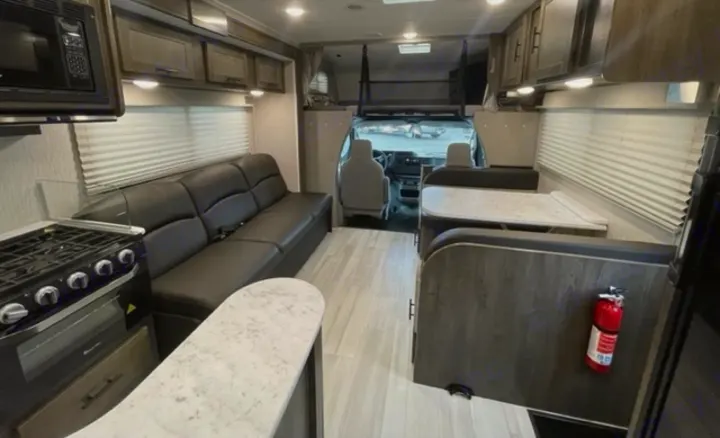 Spacious RV rental interior featuring a kitchen with stove, sofa, and dining area, perfect for comfortable travel.. Other Leprechaun 2022
