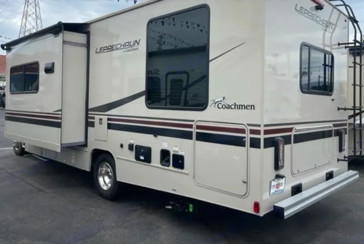 Detailed view of a cream and brown rv rental, showcasing its extended slide-out, utility bays, and rear ladder.. Other Leprechaun 2022