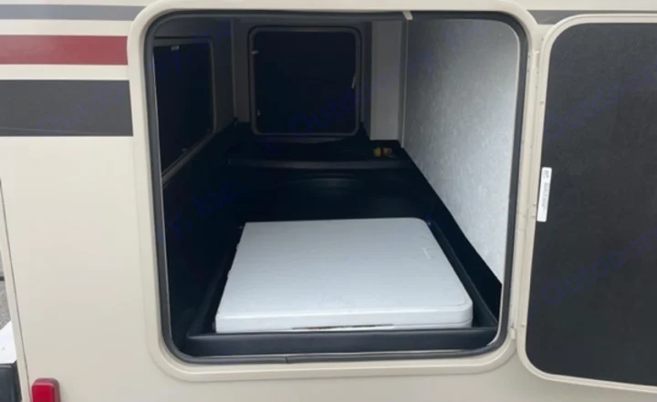 An open exterior storage bay on an RV rental reveals a folded white table. Perfect for travel gear and supplies.. Other Leprechaun 2022