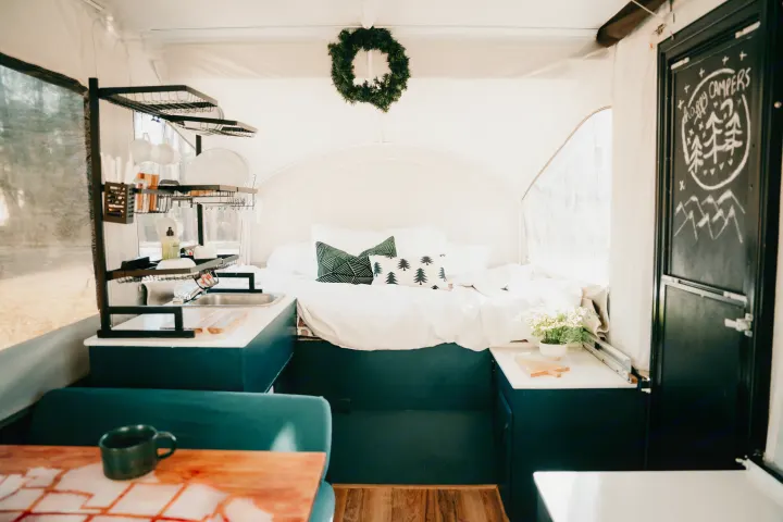 Cozy RV rental interior featuring a comfy bed, compact kitchen with sink, and a "Happy Campers" chalkboard door.. Jayco Jay 2015