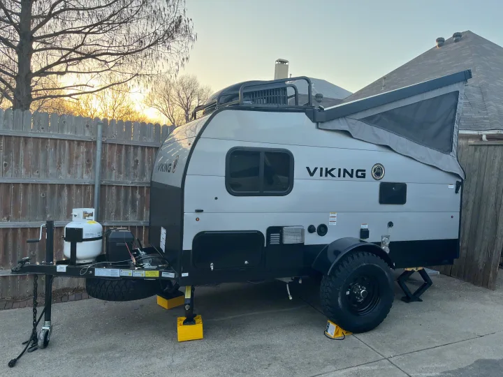 A gray and black Viking pop-up travel trailer, well-equipped for rv rental, parked on concrete with stabilizing jacks.. Forest River Viking TD 2022