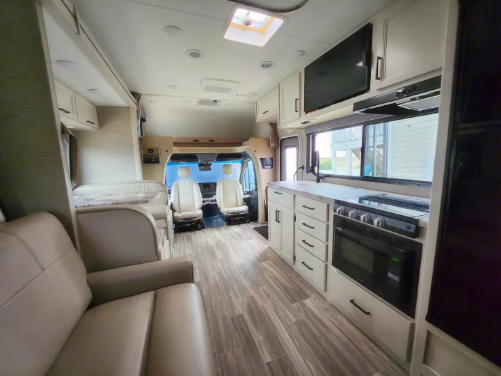 This spacious RV rental interior features a modern living area, full kitchen, and front cockpit, ready for comfortable travels.. Thor Motor Coach Four Winds 2023