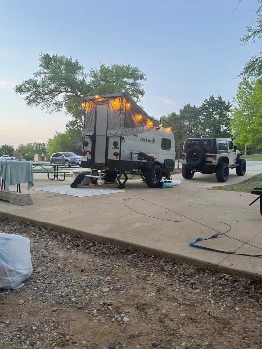RV rental: A Viking pop-up camper with string lights is set up at a campsite next to a Jeep Wrangler at dusk.. Forest River Viking TD 2022