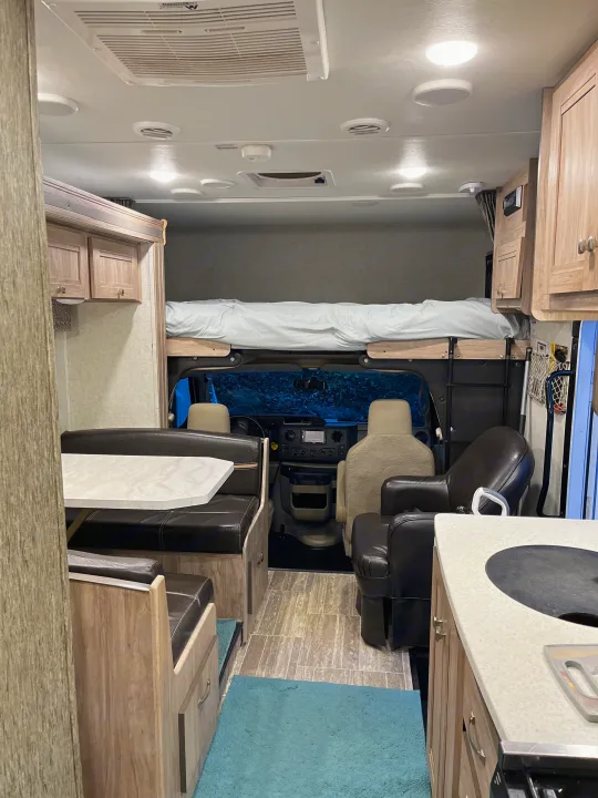 Explore this rv rental's welcoming interior: a dining nook, compact kitchen, and overhead bed above the cab.. Forest River Sunseeker 2019