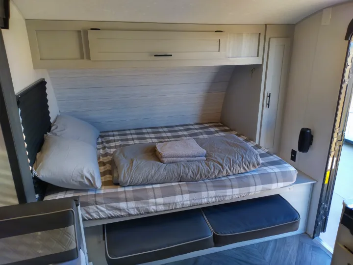 RV rental: Interior view of a cozy bed with plaid bedding, overhead storage, and pull-out seating below.. Forest River Other 2022