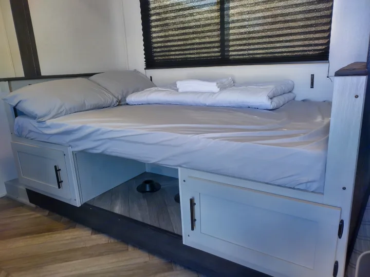 This rv rental features a clean, organized bedroom with a made bed, folded linen, and under-bed storage for efficiency.. Forest River Other 2022