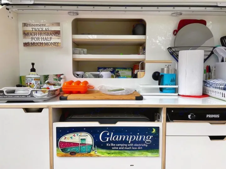 A compact, neatly organized RV rental kitchen area, featuring a portable sink, Primus stove, and clever storage solutions for glamping.. droplet XL 2026