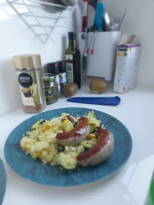 Sausages with couscous & veggies, ready to eat. Kitchen counter with coffee, spices, kiwis. Ideal for an RV rental meal.. droplet XL 2026
