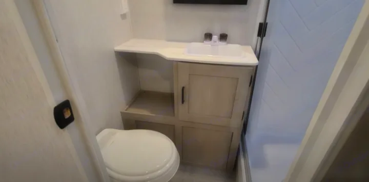 Compact RV rental bathroom featuring a toilet, sink vanity, and shower stall, designed for efficient travel.. Forest River Other 2023