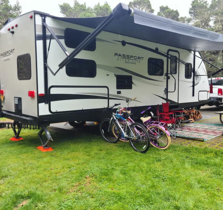 RV rental: Travel trailer at a campsite with an extended awning, bikes, chairs, and firewood.. Keystone RV Passport Grand Touring 2018