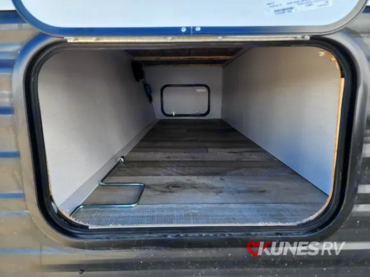 View inside an RV rental's pass-through storage compartment, showing wood-look floor & light interior walls.. Keystone Springdale 2022