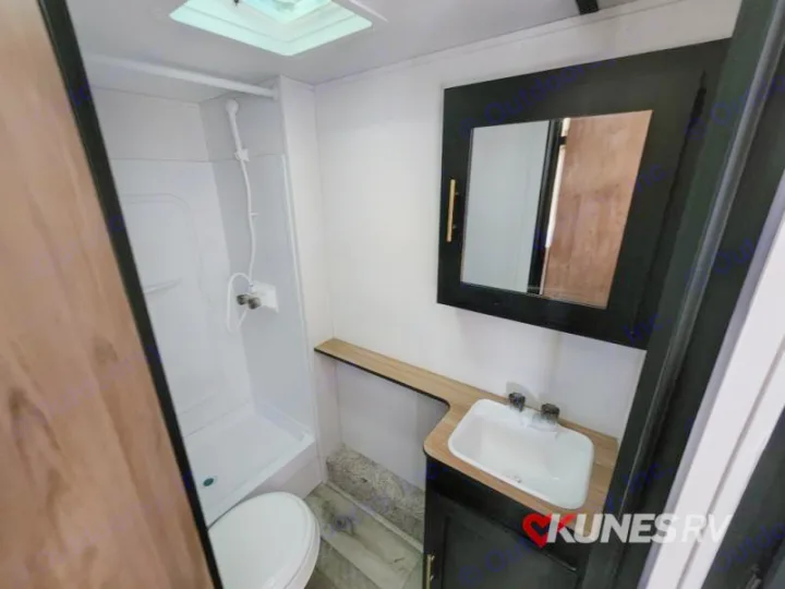 Clean RV rental bathroom featuring a shower stall, toilet, and vanity with a sink and mirror. Compact and functional.. Keystone Springdale 2022