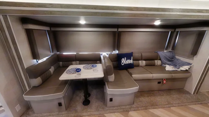 Cozy RV rental dinette featuring U-shaped seating, a table with place settings, and window blinds.. Forest River Salem 2021