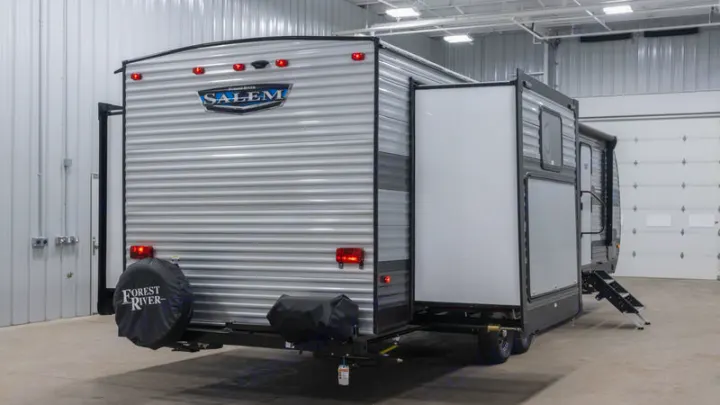 A gray Salem travel trailer with an extended side slide-out and deployed steps, perfect for your RV rental needs.. Forest River Salem 2021