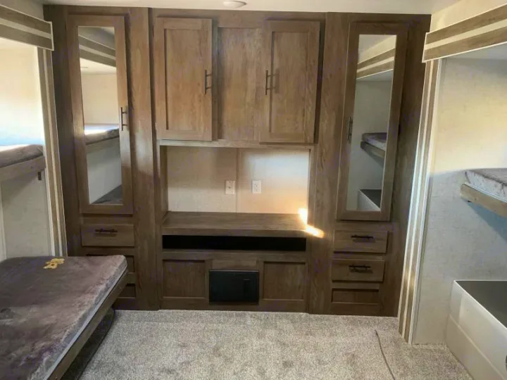 This RV rental bunkhouse features a clever built-in storage unit, mirrored cabinets, and comfortable bunk beds for travelers.. Forest River Salem 2021