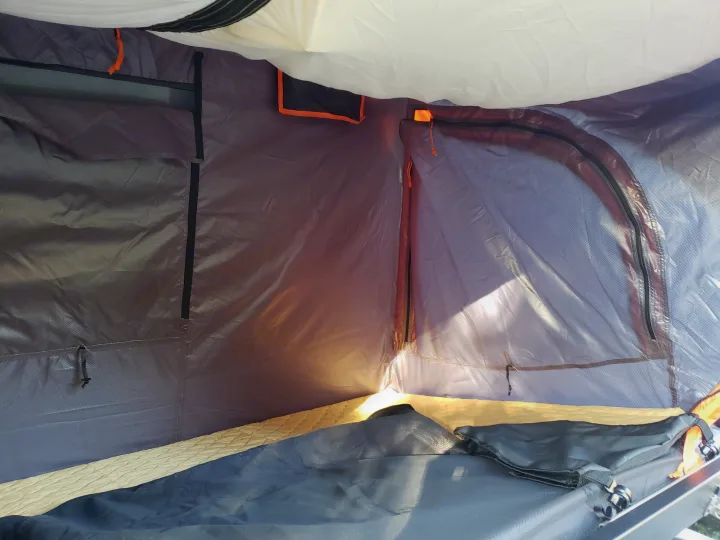 Inside a cozy RV rental tent: a comfortable sleeping area with light filtering through the mesh window.. Nissan Exterra 2011