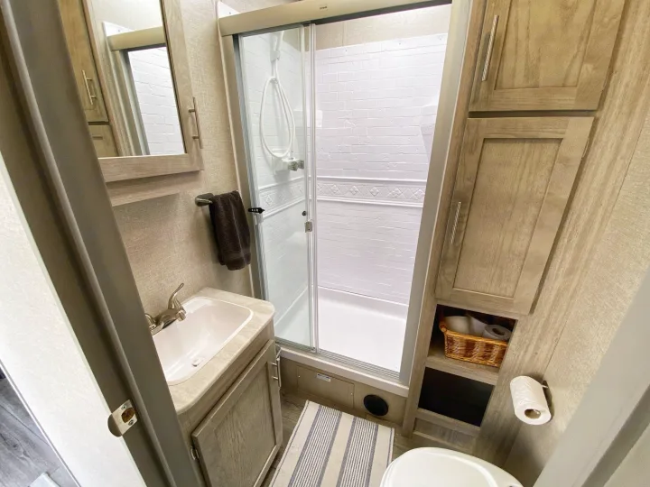 Step inside this clean RV rental bathroom, complete with a shower, vanity with sink, toilet, and practical storage solutions.. Coachmen Catalina 2022