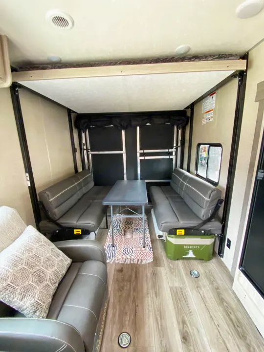 RV rental interior: A living/dining space with gray benches, central table, and overhead bed platform.. Coachmen Catalina 2022