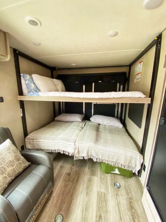 RV rental interior shows bunk beds (upper single, two lower singles) and a recliner, maximizing compact living space.. Coachmen Catalina 2022