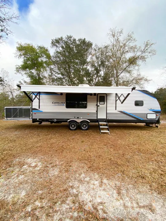 Catalina Trailblazer toy hauler RV rental ready for adventure. This travel trailer is parked outdoors with an extended ramp.. Coachmen Catalina 2022
