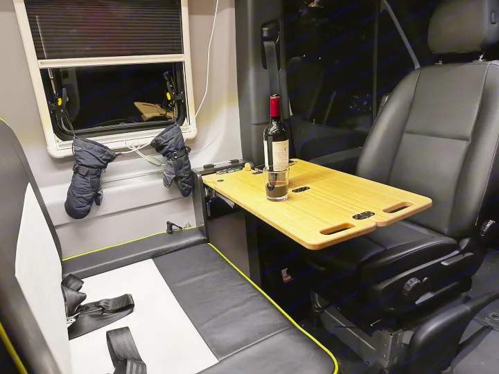 Cozy rv rental interior featuring a window, hanging gloves, and a bamboo table with wine, showcasing comfortable seating for travel.. Winnebago Revel 2020