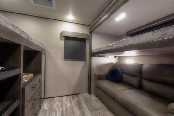 Inside a modern RV rental, featuring bunk beds, a comfy sofa, and smart storage.. Grand Design Reflection 2022