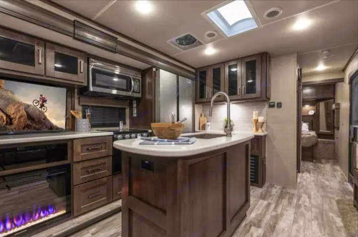Luxury RV rental interior with a full kitchen, TV/fireplace, and cozy bedroom, perfect for your next adventure.. Grand Design Reflection 2022