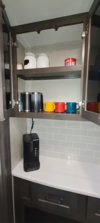 Organized RV rental kitchen cabinet with mugs, canisters, and a coffee maker on the counter.. Grand Design Reflection 2022