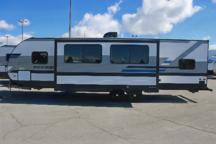 A sleek grey and white travel trailer RV, perfect for rv rental, parked on a sunny day. Features blue accents and multiple windows.. Heartland RVs Pioneer 2021