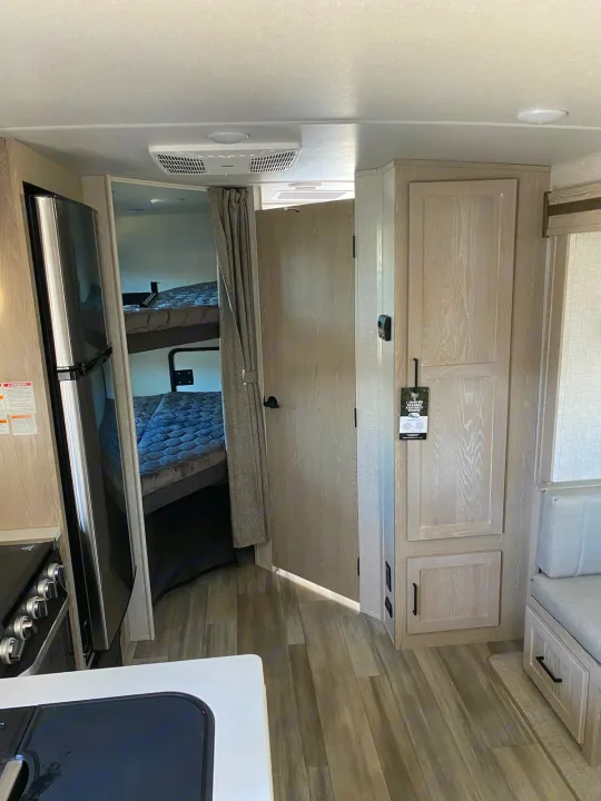 Spacious RV rental interior with modern bunk beds, overhead cabinets, and a compact kitchen area.. Flagstaff Microlite 2023