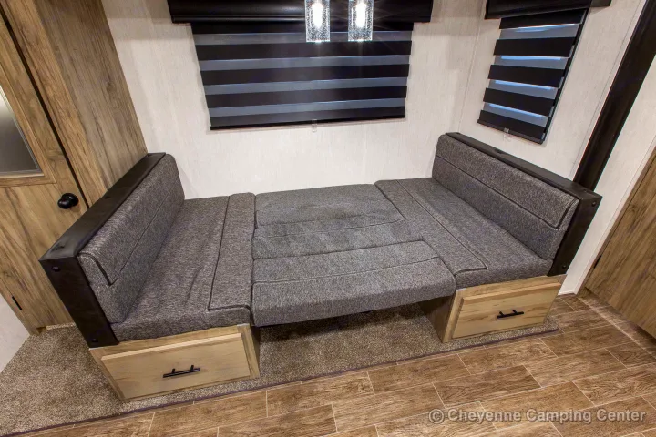 RV rental dinette setup: gray bench seating converts to a bed, with under-seat storage drawers & windows.. Forest River Cherokee Alpha Wolf 2022